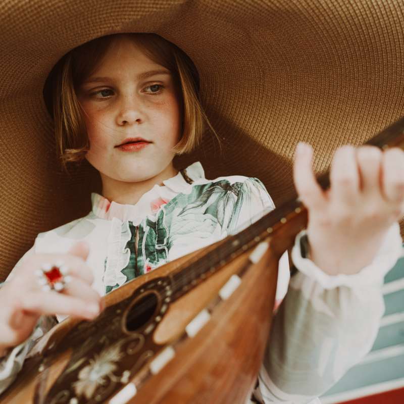 Young girl learning to play mandolin in mandolin lessons.