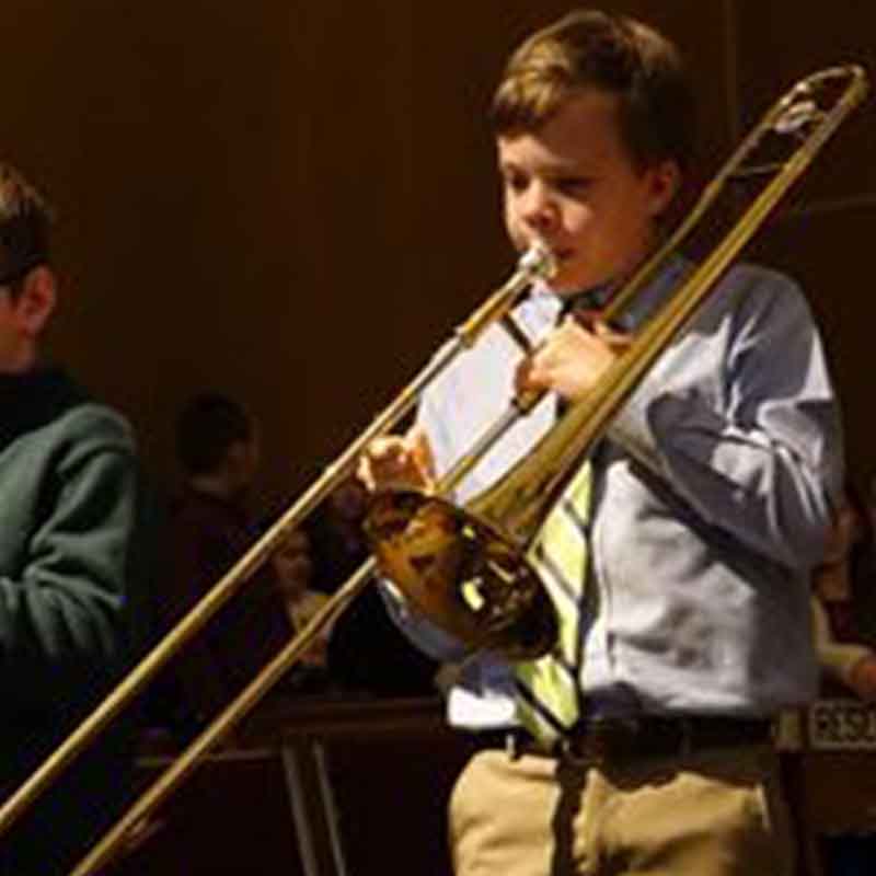 Young boy learning to play trombone in private trombone lessons.